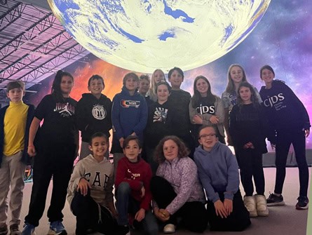 Group of CJDS students in front of giant planet display at museum